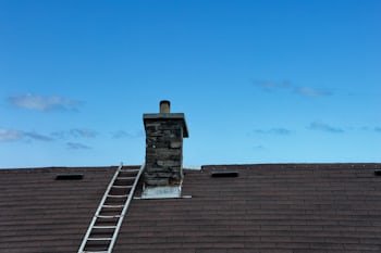 Chimney with a ladder set up for service, similar to homes throughout Cincinnati, OH